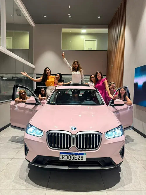 Consultoras comemorando ao redor de um BMW rosa